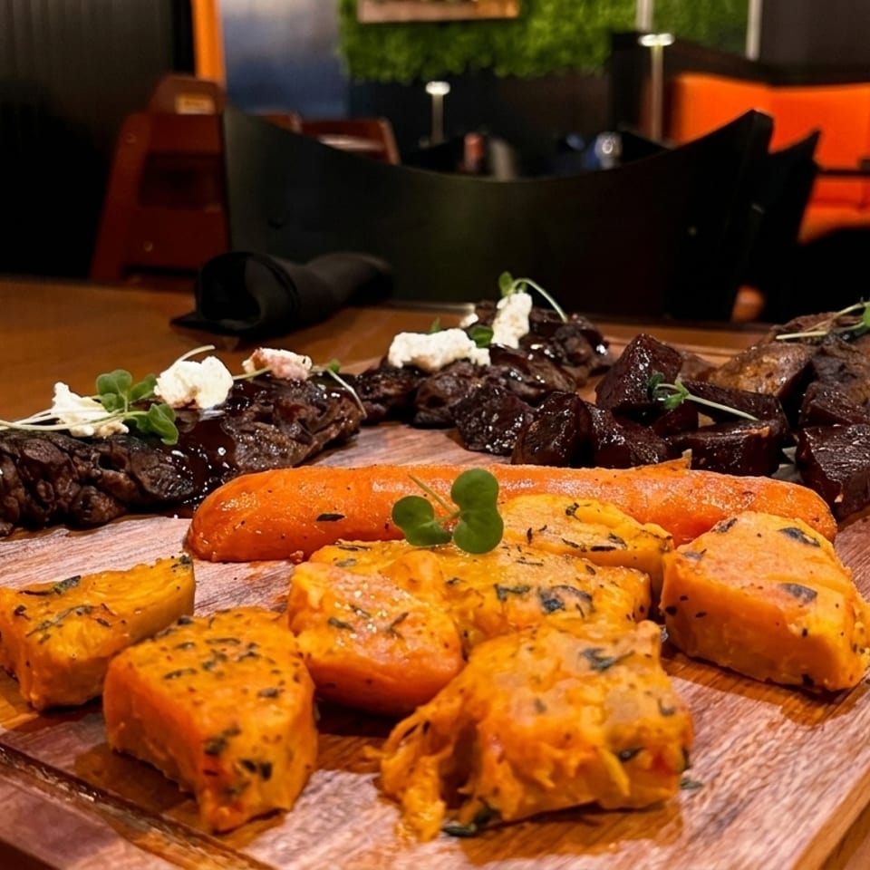 A wooden board with steak, roasted carrots, sweet potatoes, and beets with feta cheese.
